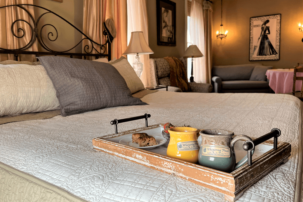 Bedroom bed with iron headboard, and tray sitting on bed with mugs and pastries
